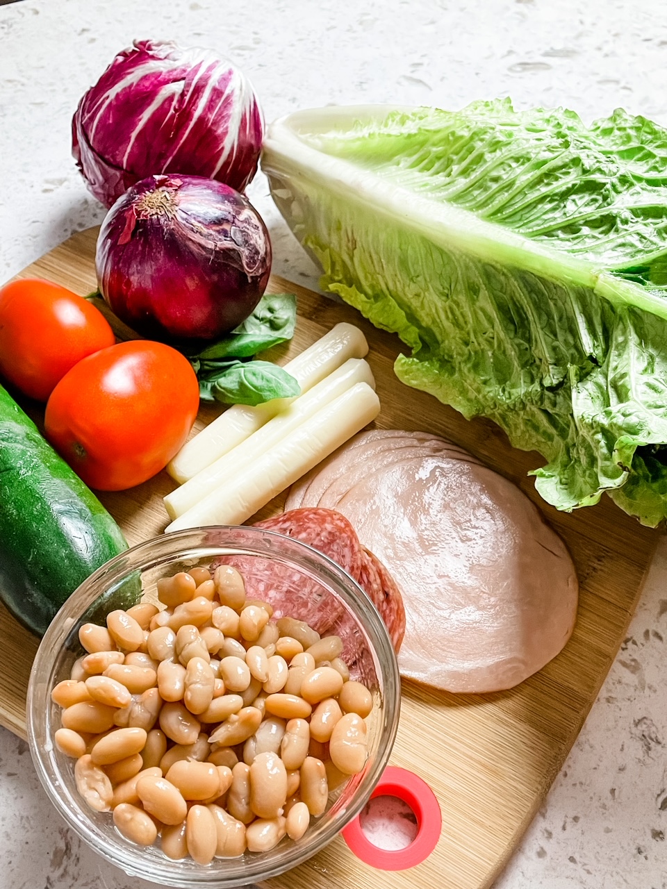 The ingredients on a cutting board - vegetables, salami, and beans