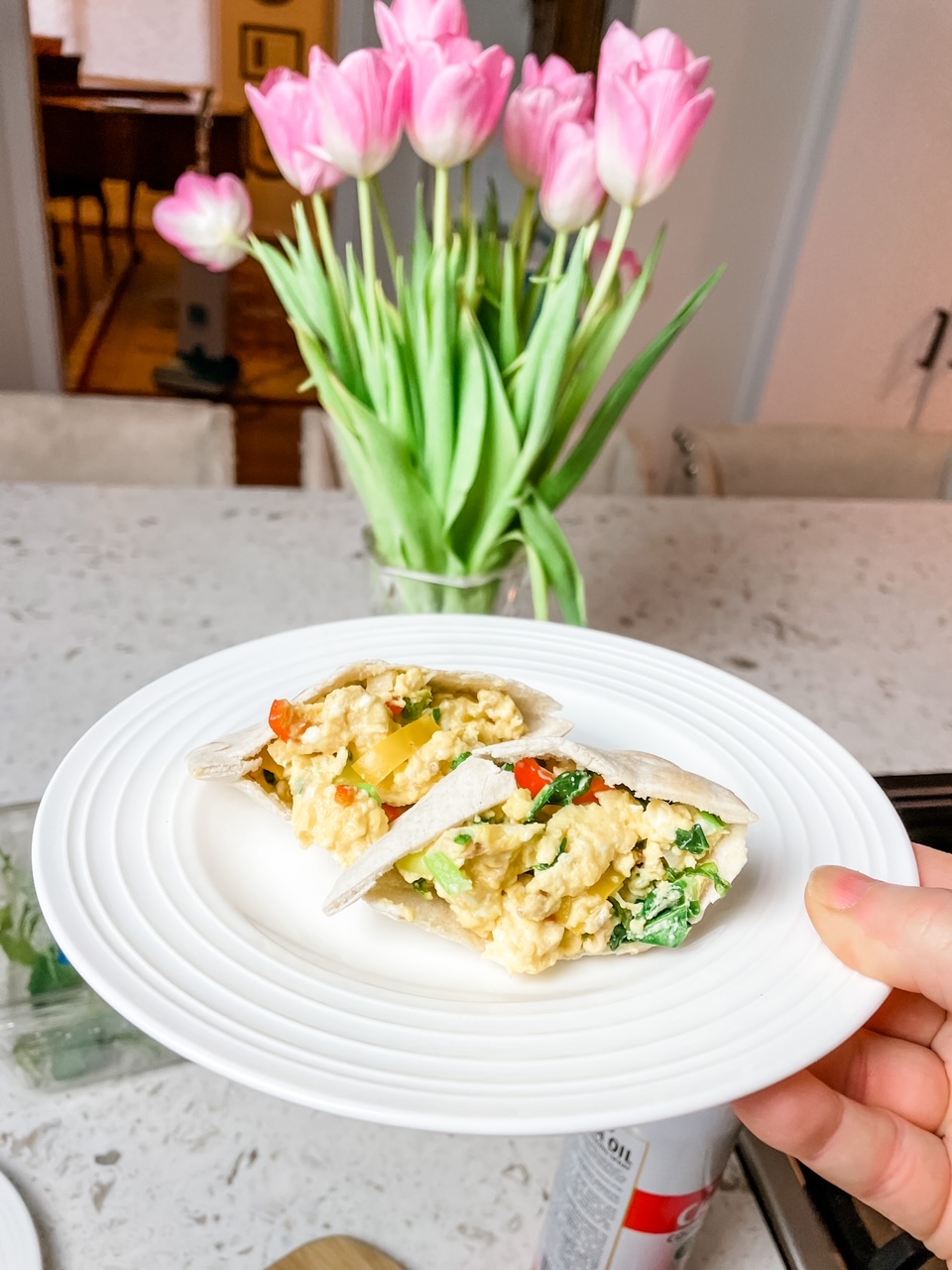 Quick and Healthy Breakfasts: The veggie Scramble Pitas on a plate, with a bouquet of flowers in the background.