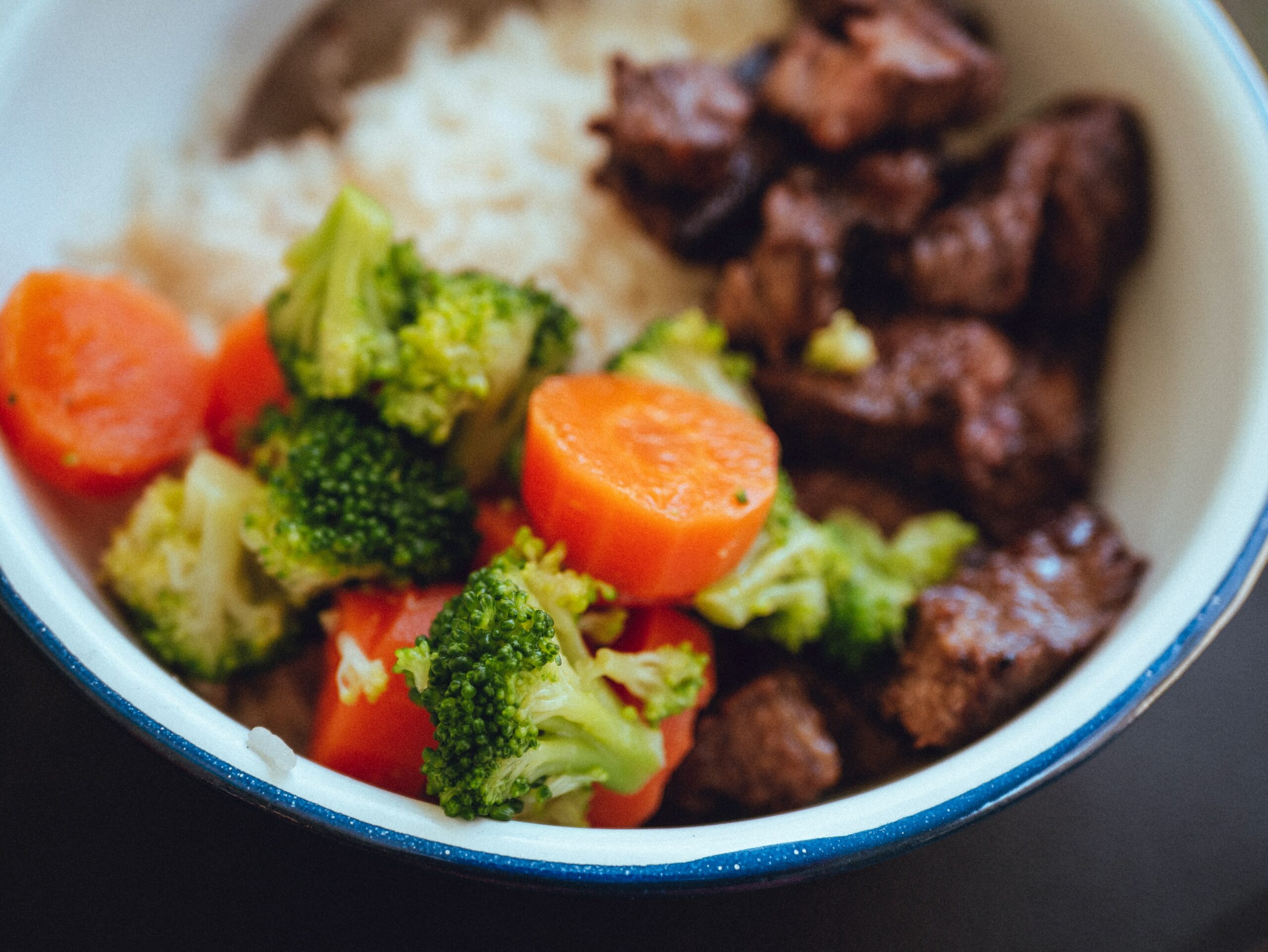 A bowl with vegetables, rice, and beef