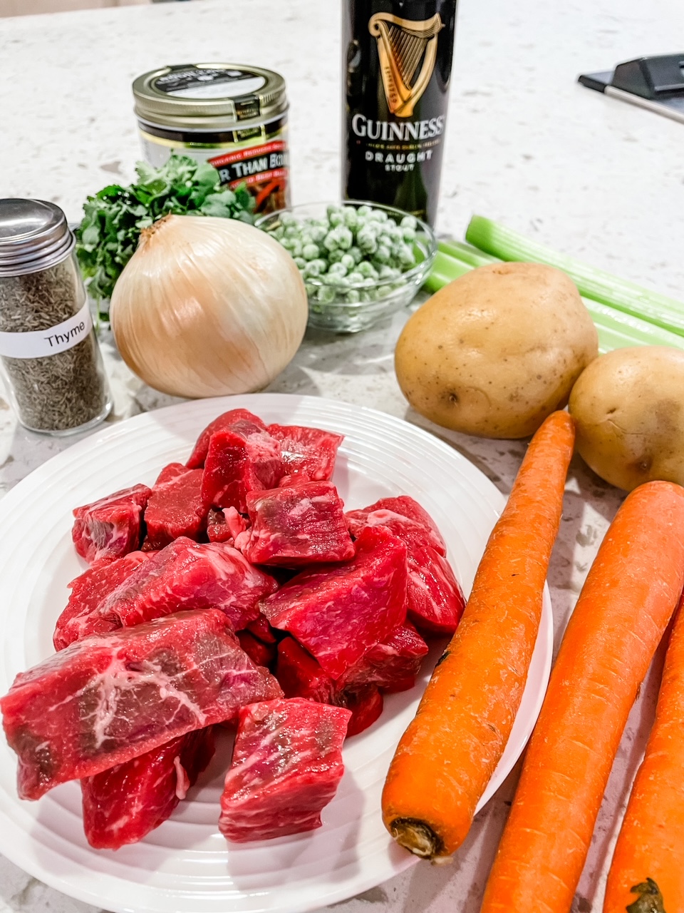 The ingredients, including an onion, cubed beef, carrots, and greens