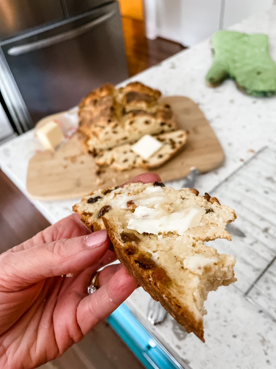 A hand holding a buttered piece of the Easy Irish Soda Bread