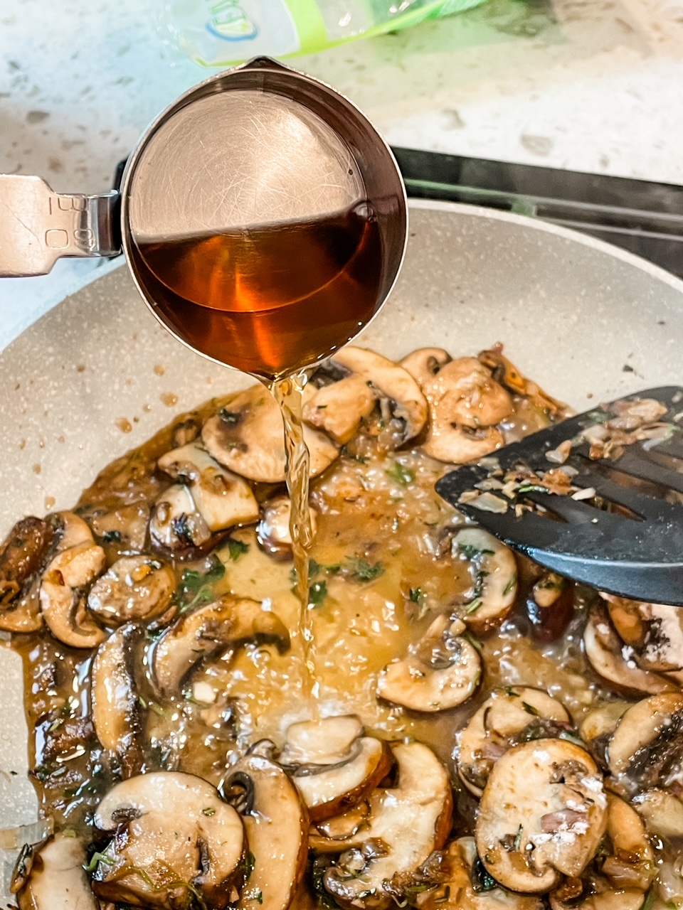 The marsala wine being poured into the sauce for the Healthier Chicken Marsala