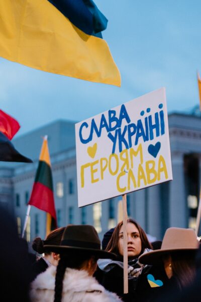 A protest with a woman holding a sign that says 'Save Ukraine'