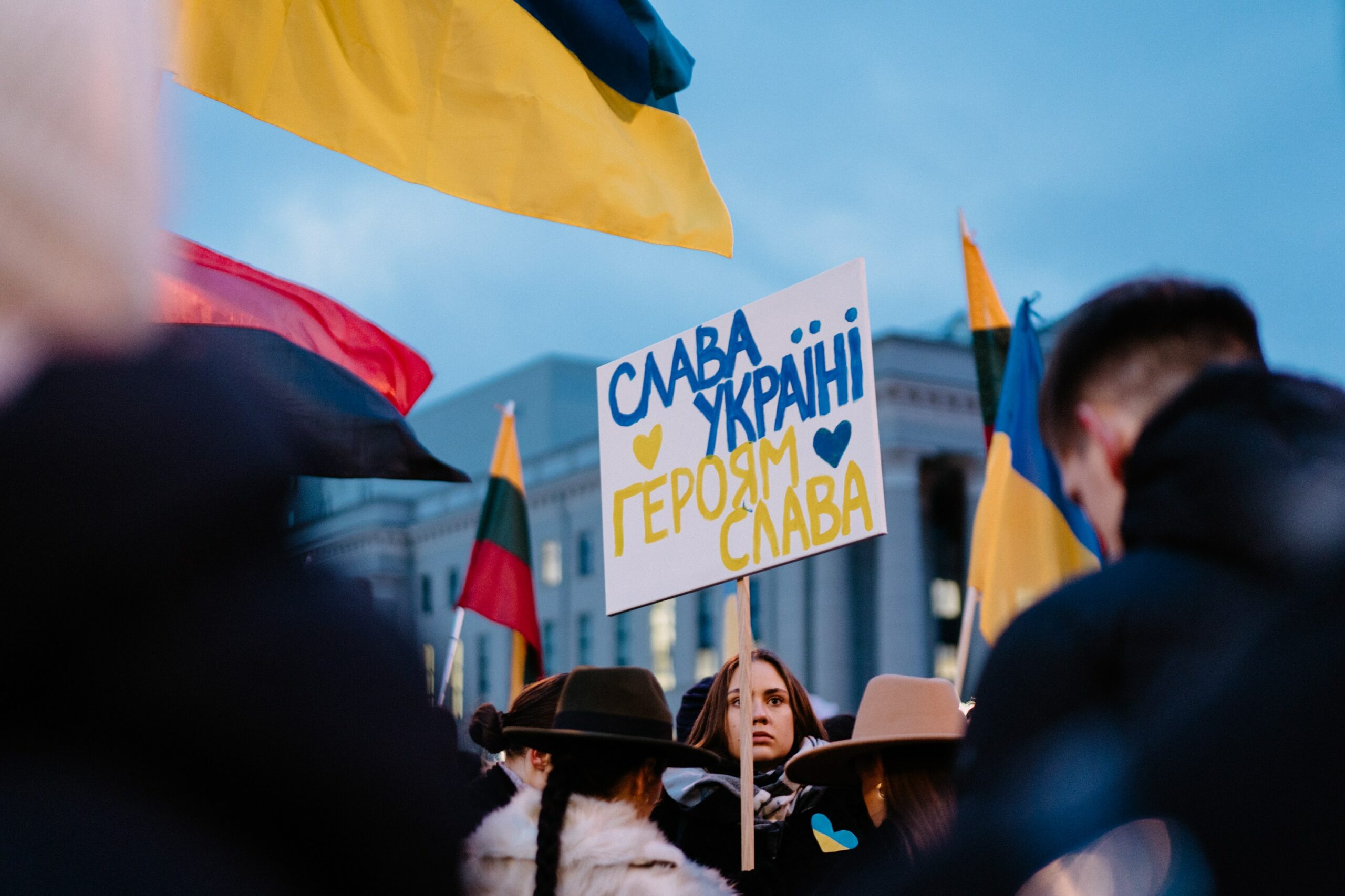 A protest with a woman holding a sign that says 'Save Ukraine'