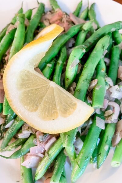 A close-up of the Green Beans with Dill and Lemon topped with a sliced lemon