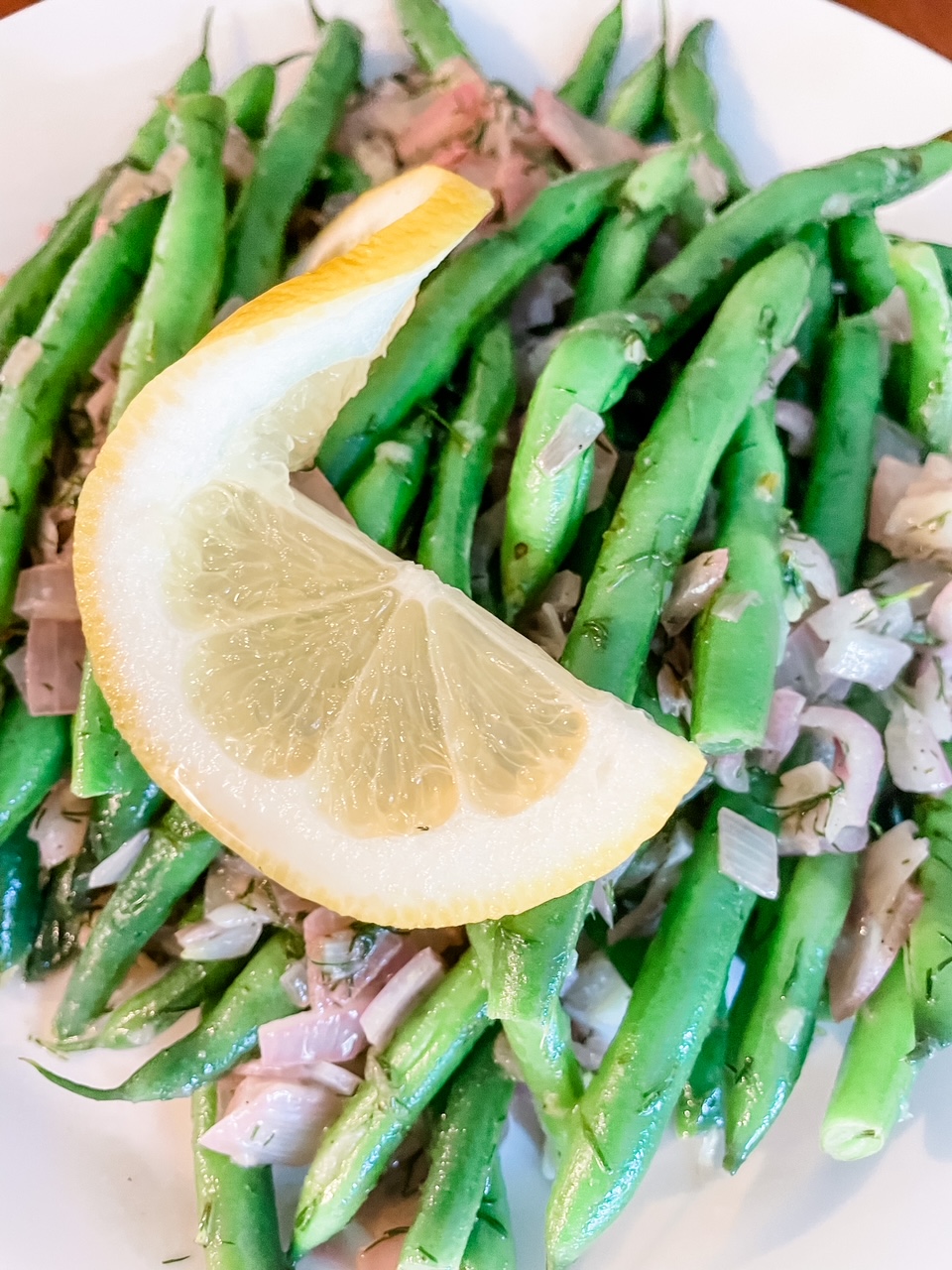 A close-up of the Green Beans with Dill and Lemon topped with a sliced lemon