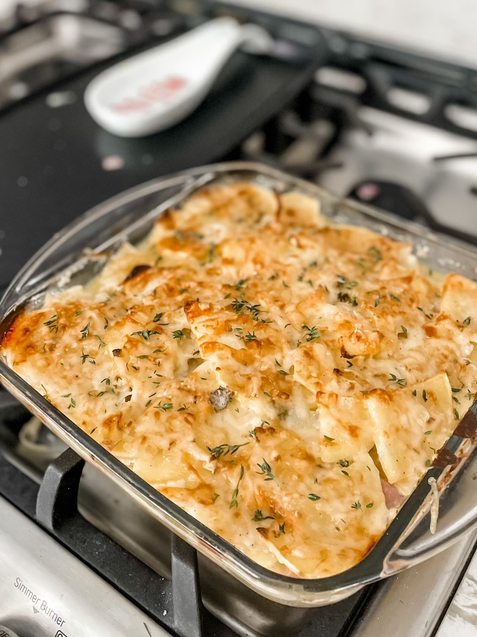 The finished Sweet Potato Gratin with Ham in a glass baking dish cooling on the stove top