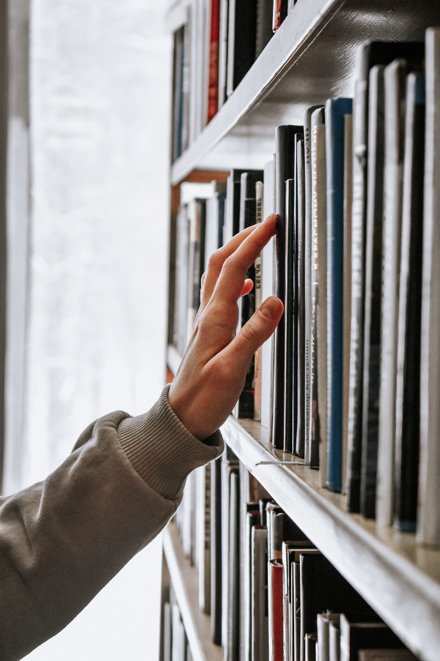 A hand placing a book back on a shelf