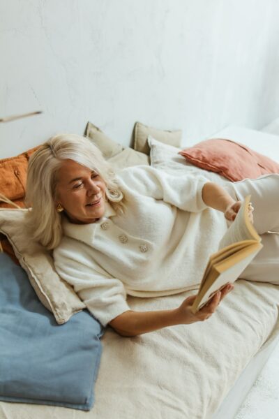 A woman reclining on her bed while reading abook