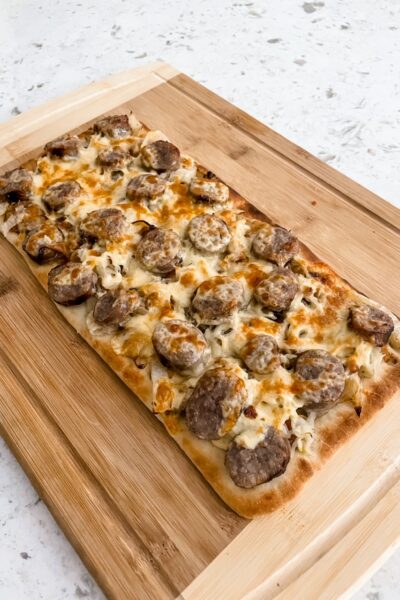 The finished Sausage, Sauerkraut and Gouda Flatbread cooling on a wooden cutting board