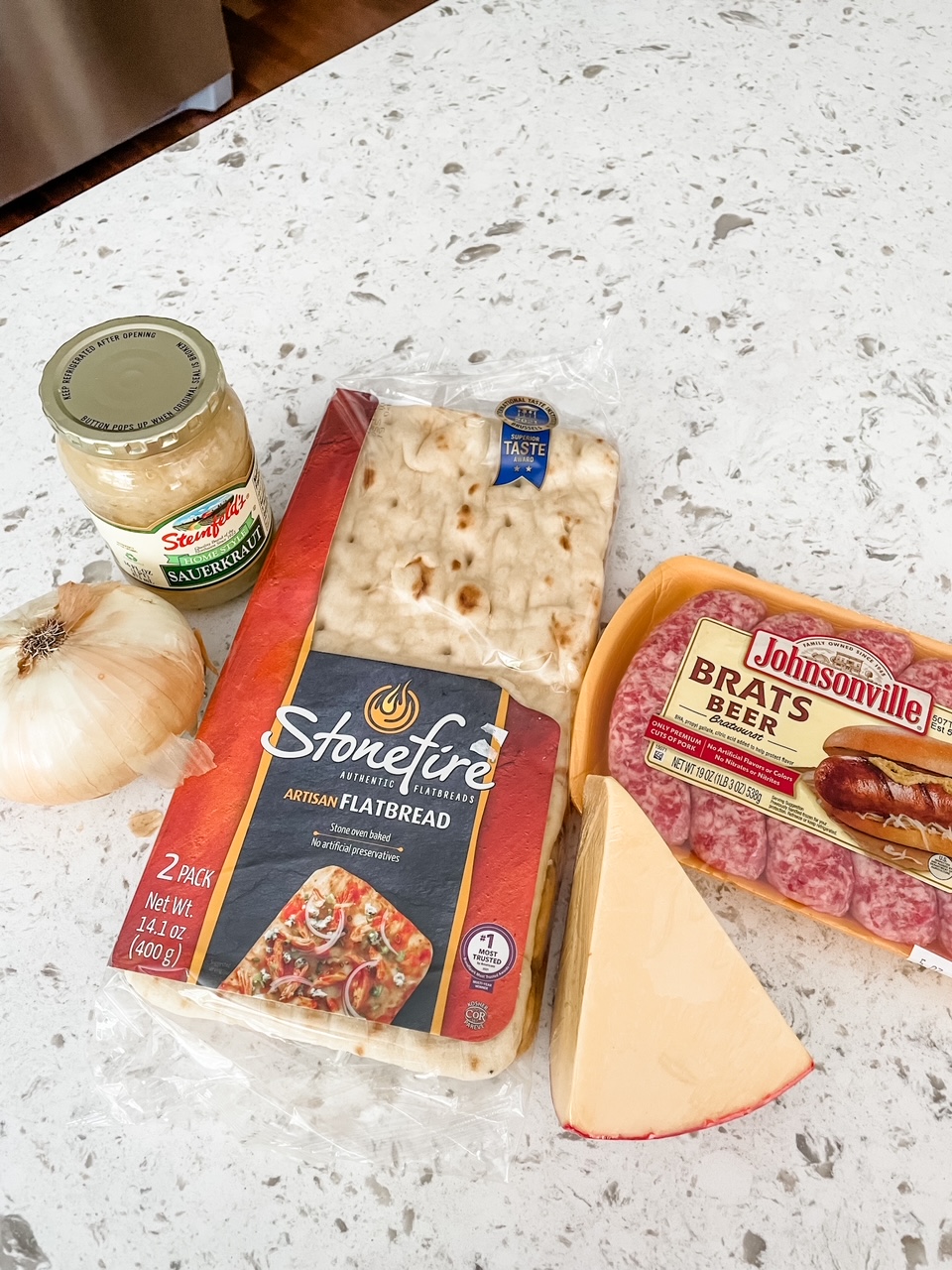 The ingredients laid out - flatbread crust, onion, sauerkraut, sausage, and cheese