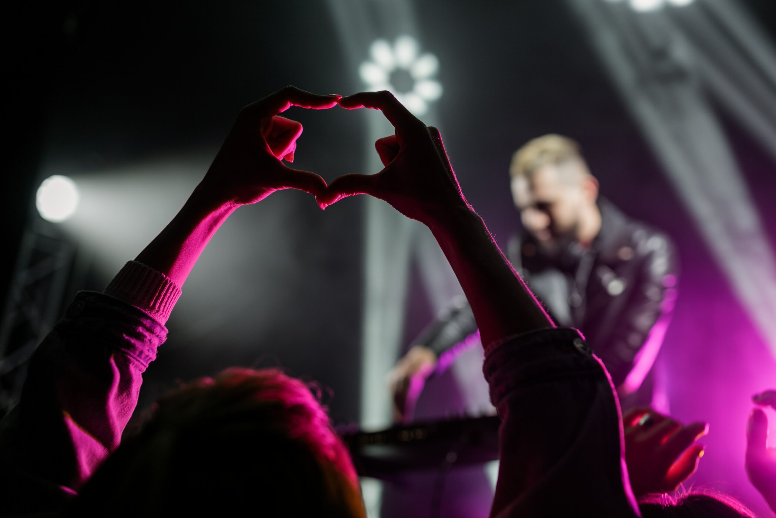 A person making a heart with their hands at a concert