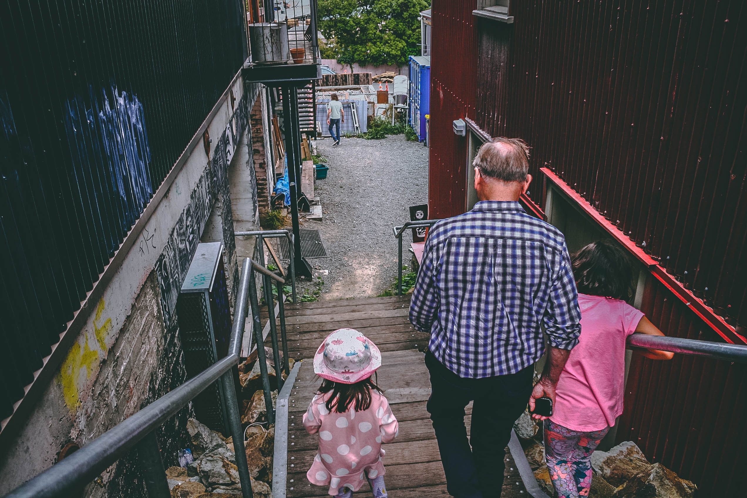 Two little girls on a trip with their grandfather, walking down some stairs into a street - one of the ideas in the The Guide to Giving Experiences as Gifts
