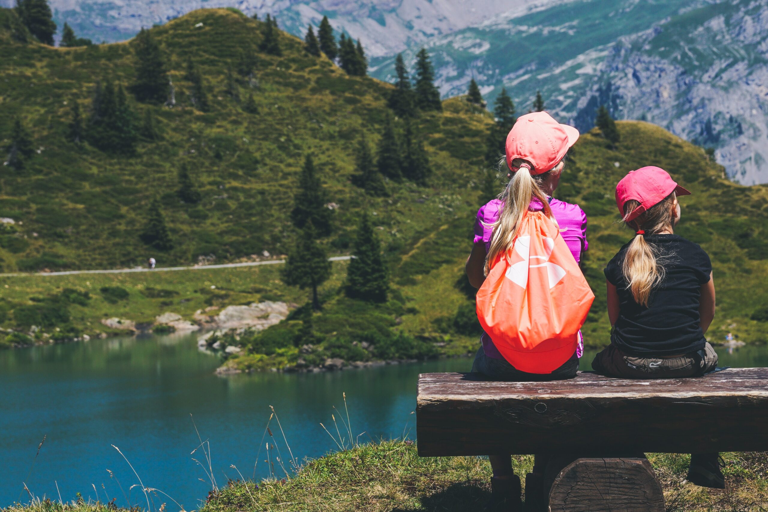 Two kids sitting on a bench overlooking a lake