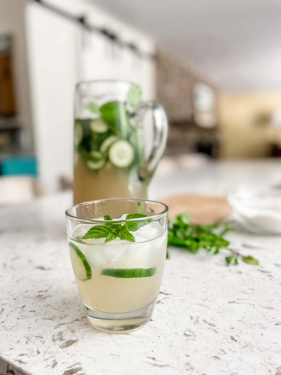 The Coconut-Lime Cucumber Mocktails in a glass and pitcher on a countertop