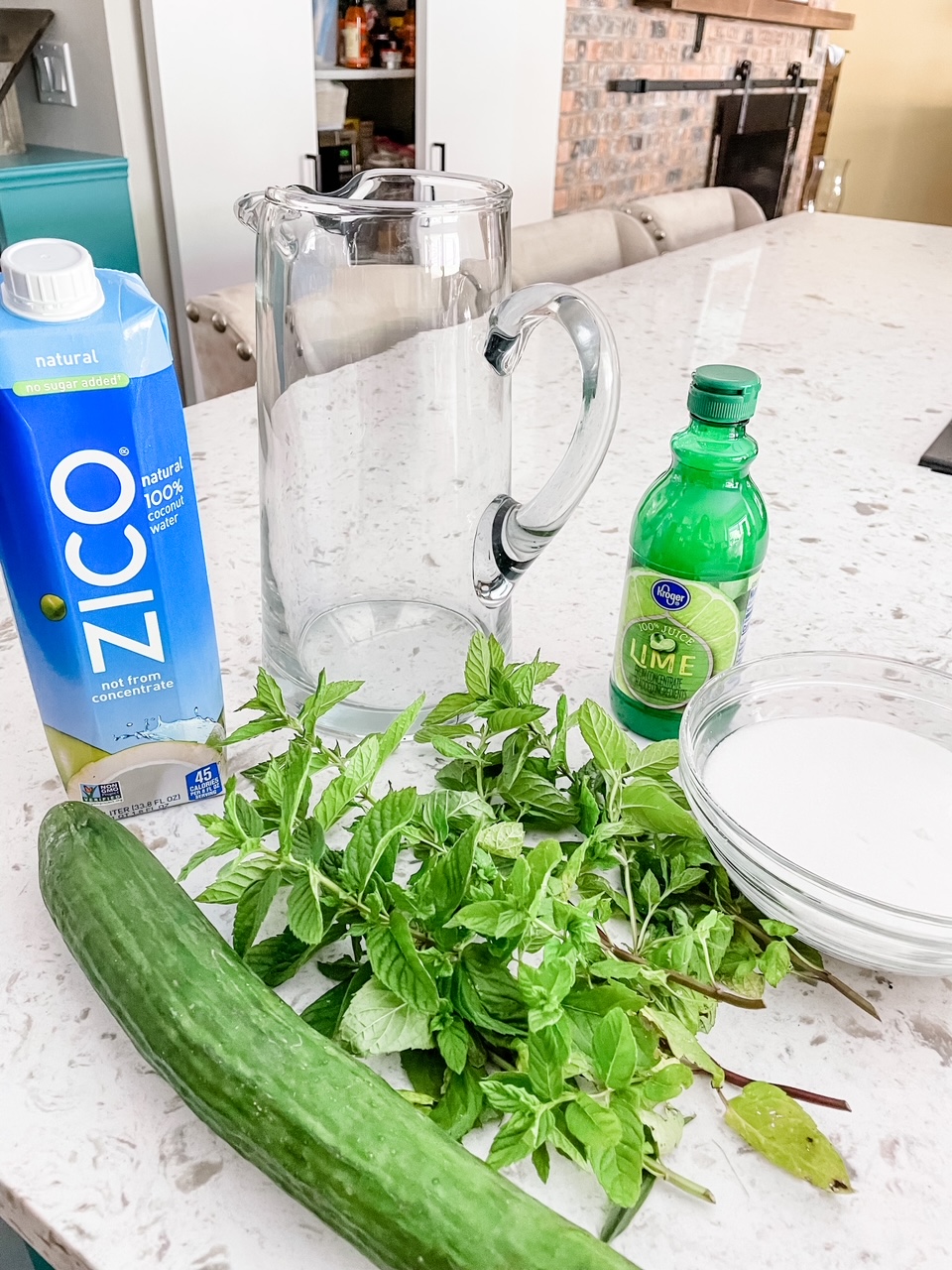 The ingredients - coconut water, cucumber, lime juice, mint, and sugar on a countertop