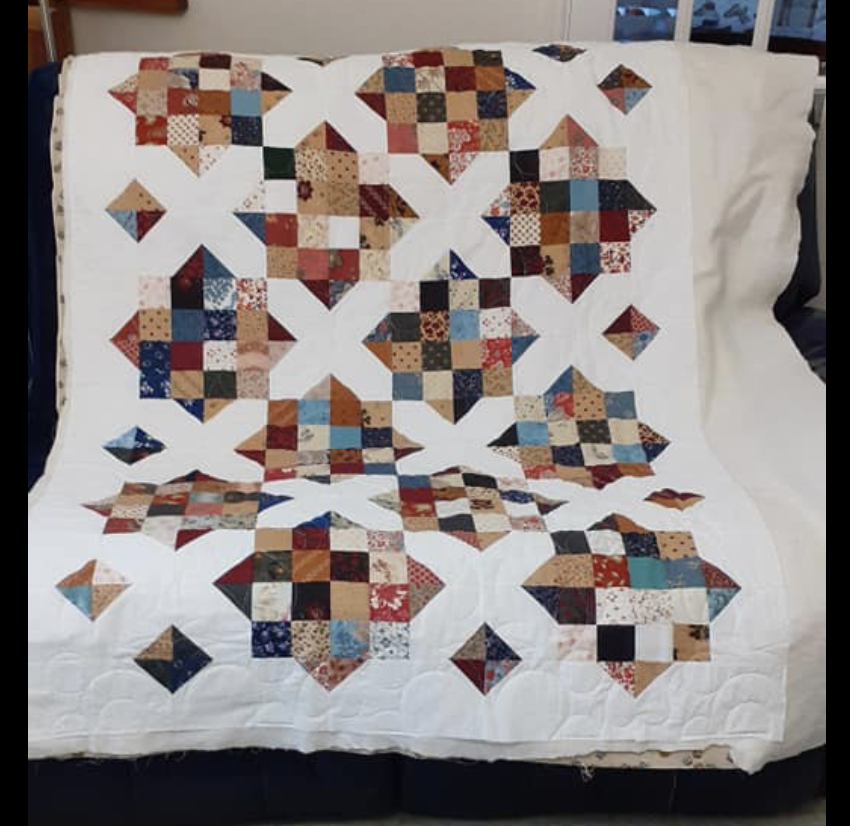 A scrappy, patchwork quilt with a white background and colorful quilt blocks