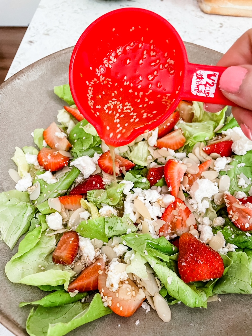 The Sesame Vinaigrette being poured over the Strawberry and Chevre Salad 