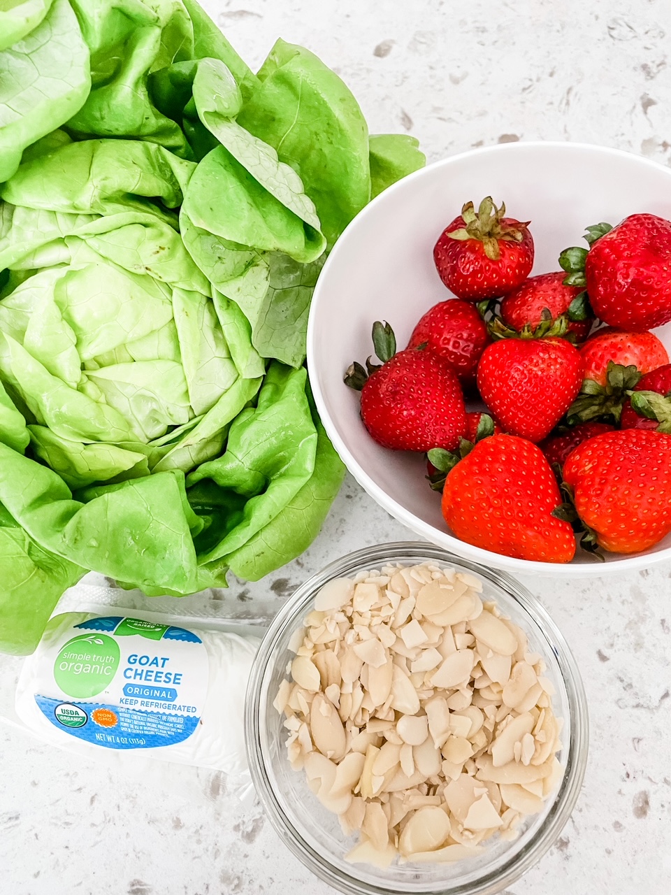 Butter lettuce, strawberries, cheese, and almonds on a counter