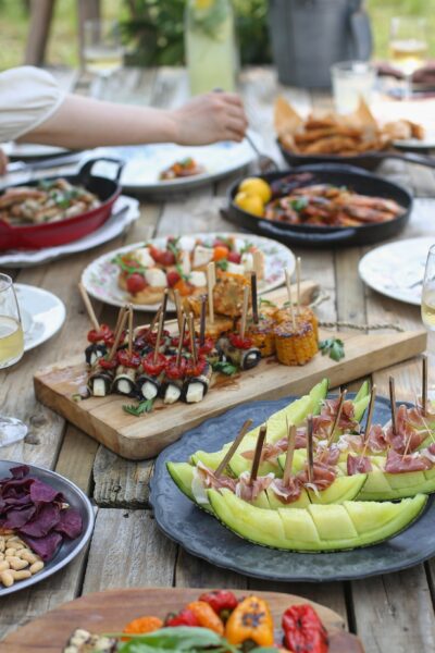 A outdoor dinner table piled with food and dishes: Recipe Guide to Easy Summer Entertaining