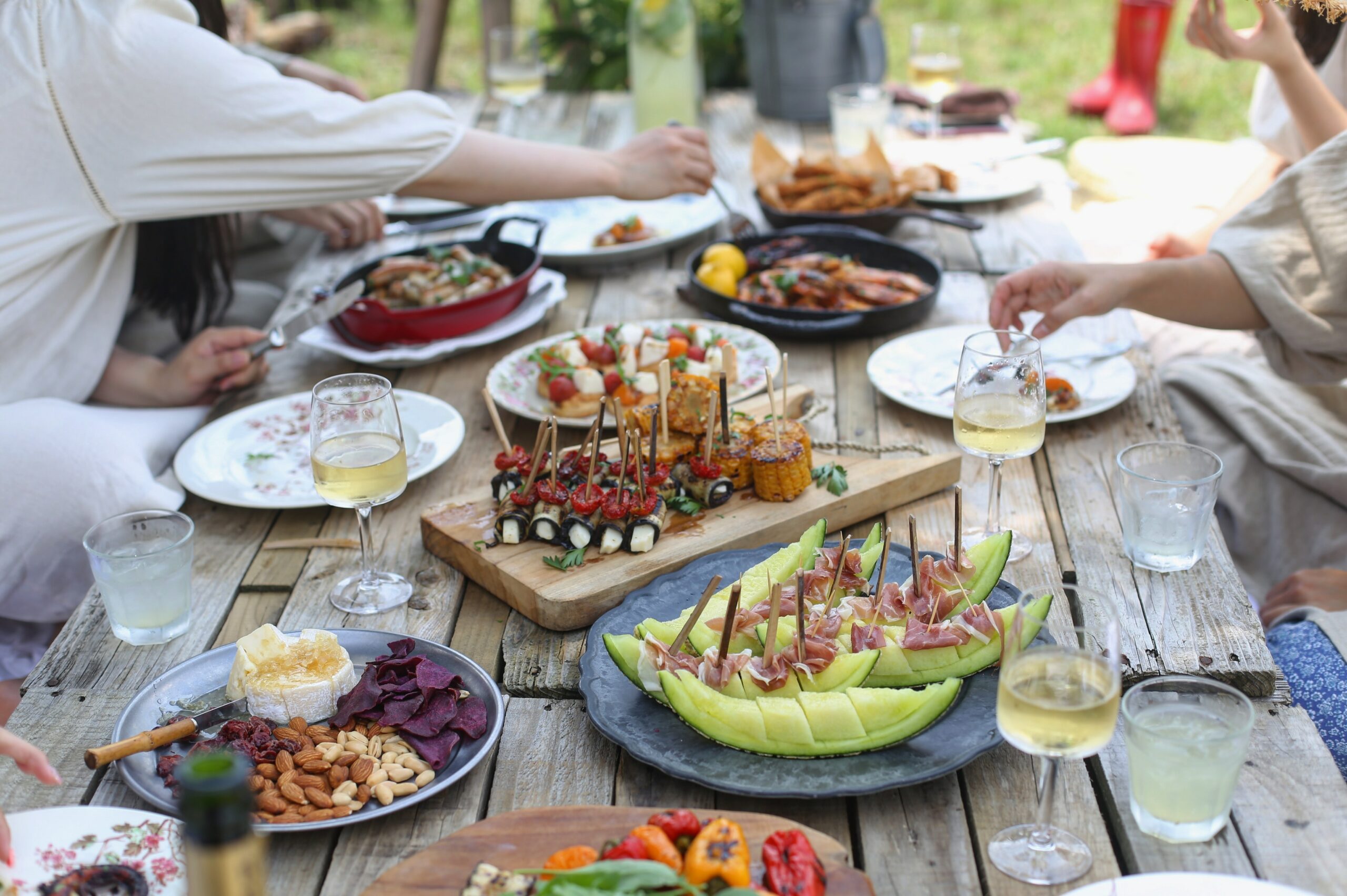 A outdoor dinner table piled with food and dishes: Recipe Guide to Easy Summer Entertaining