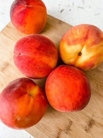 Fresh peaches on a wooden cutting board