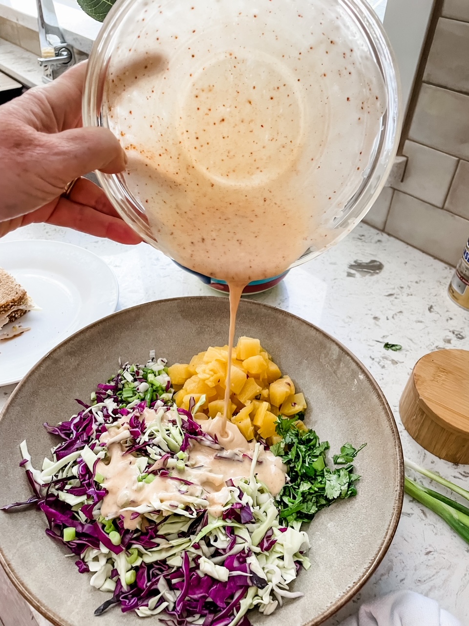 The chile-lime dressing being poured into the slaw