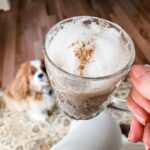 Marie holding the finished Pumpkin Spice Latte with her dog in the background