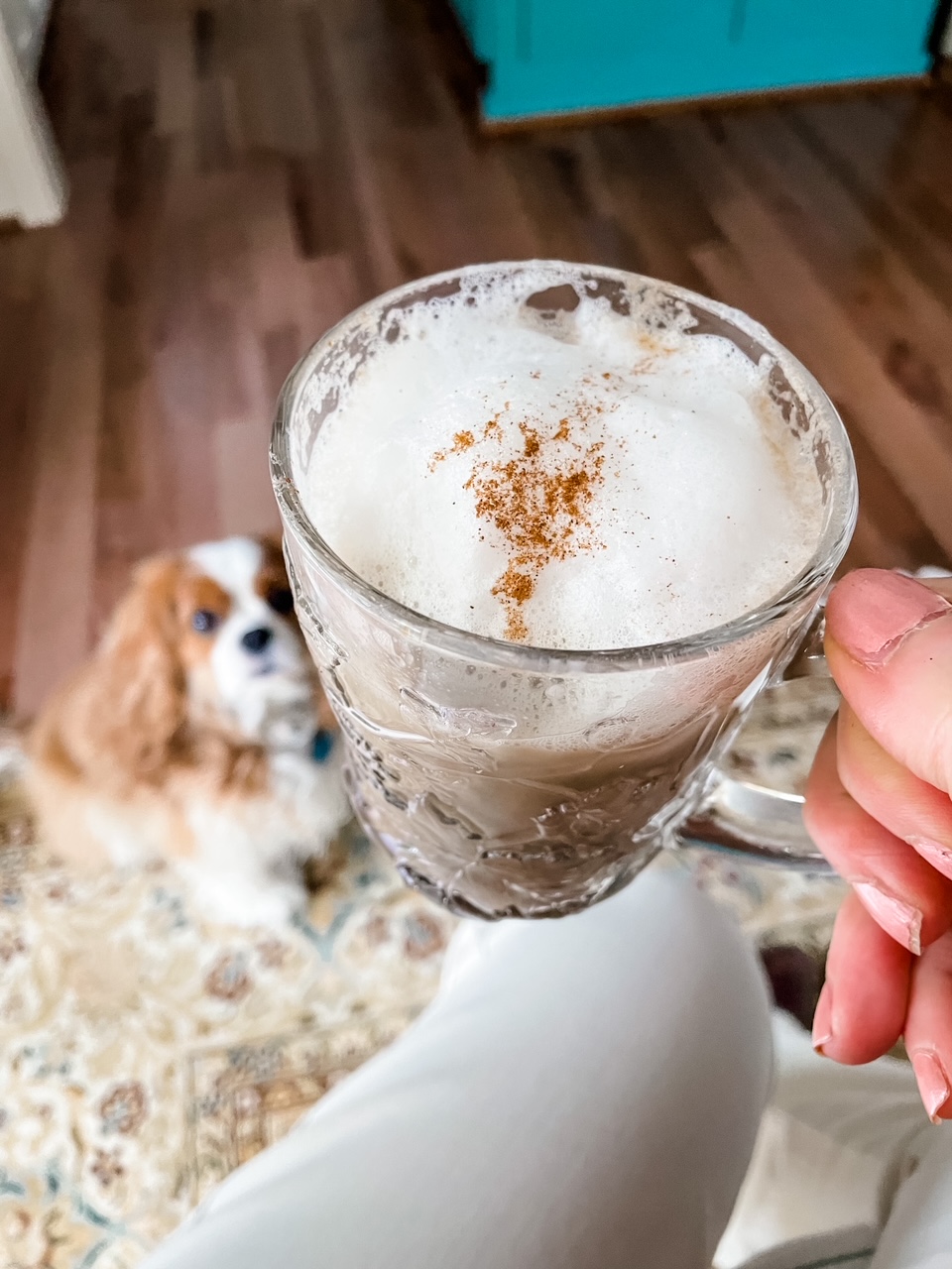 Marie holding the finished Pumpkin Spice Latte with her dog in the background