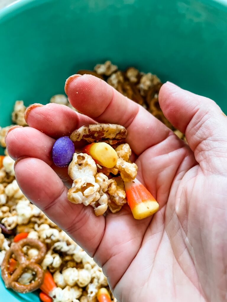 A hand holding up some of the Easy Halloween Caramel Corn Recipe