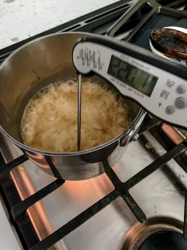 An instant-read thermometer in the caramel