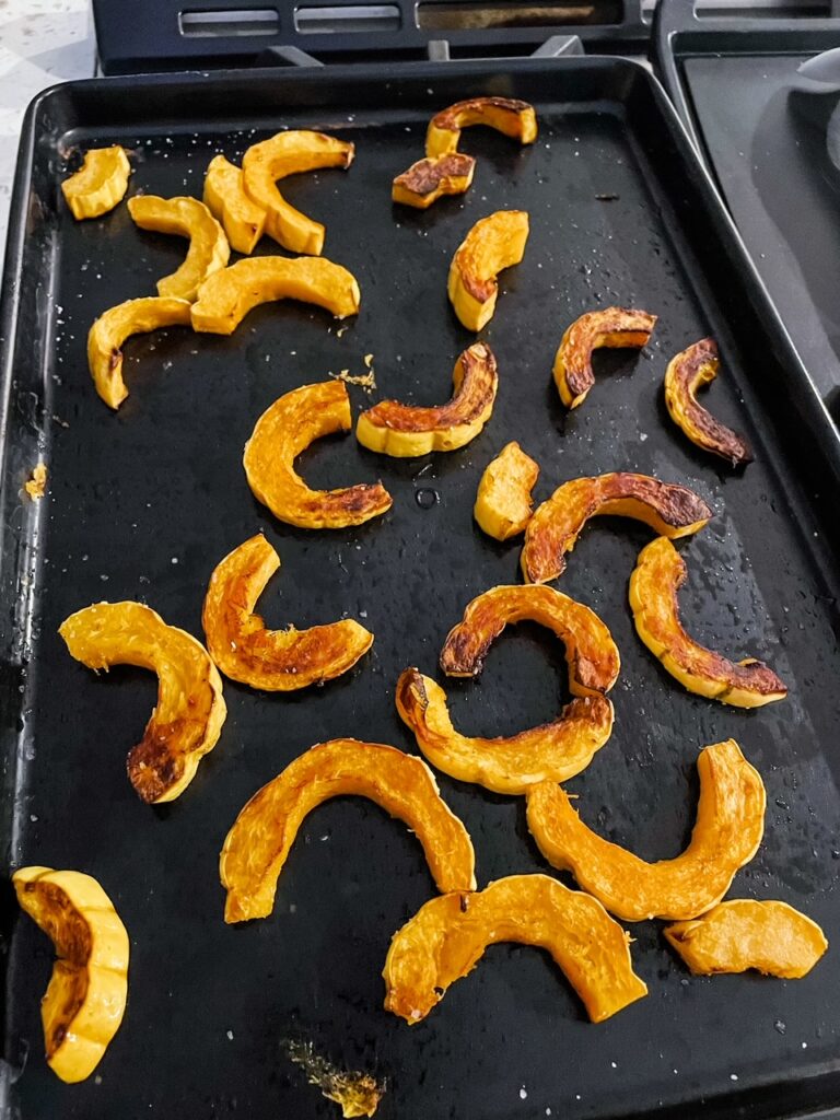 A sheet pan with the slices of roasted delicata squash