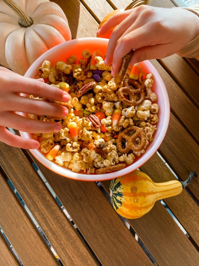 Two hands reaching into the Easy Halloween Caramel Corn Recipe