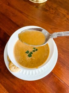 A spoon held above a bowl of Vegan Carrot and Red Lentil Soup