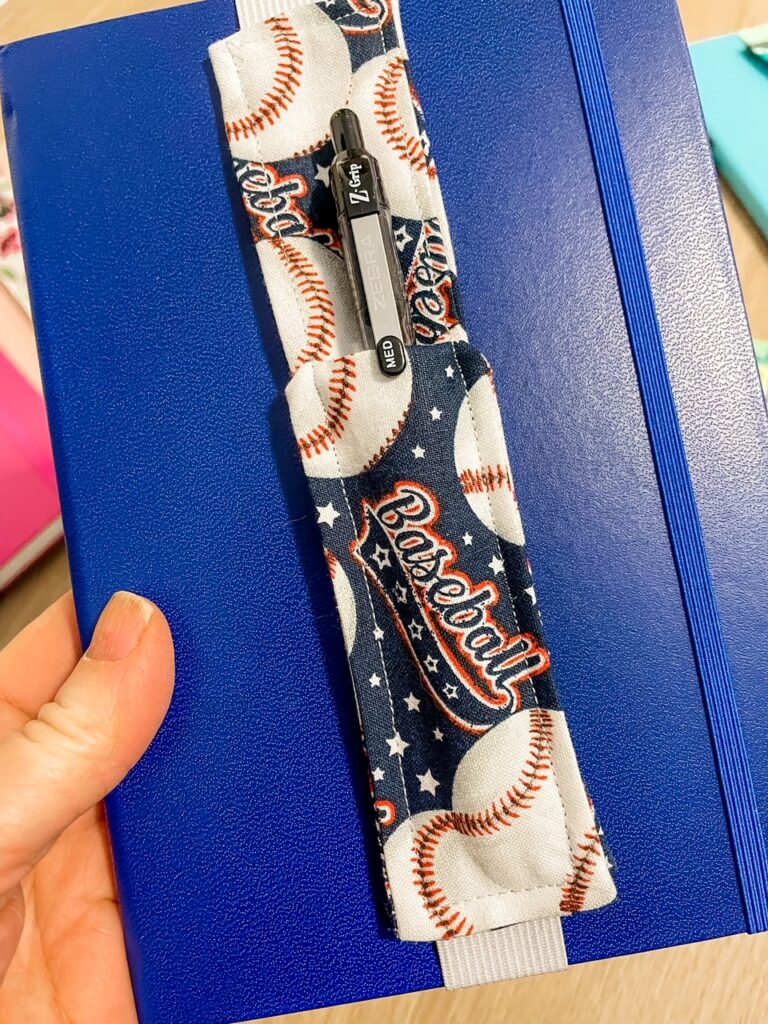 A blue notebook with a baseball version of the DIY Pen Pouches