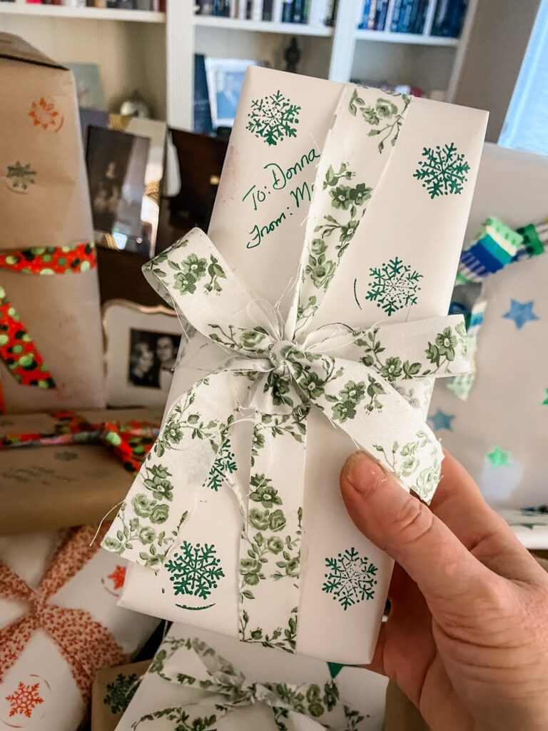 A hand holding up one of the gifts wrapped in the Homemade Sustainable Gift Wrap