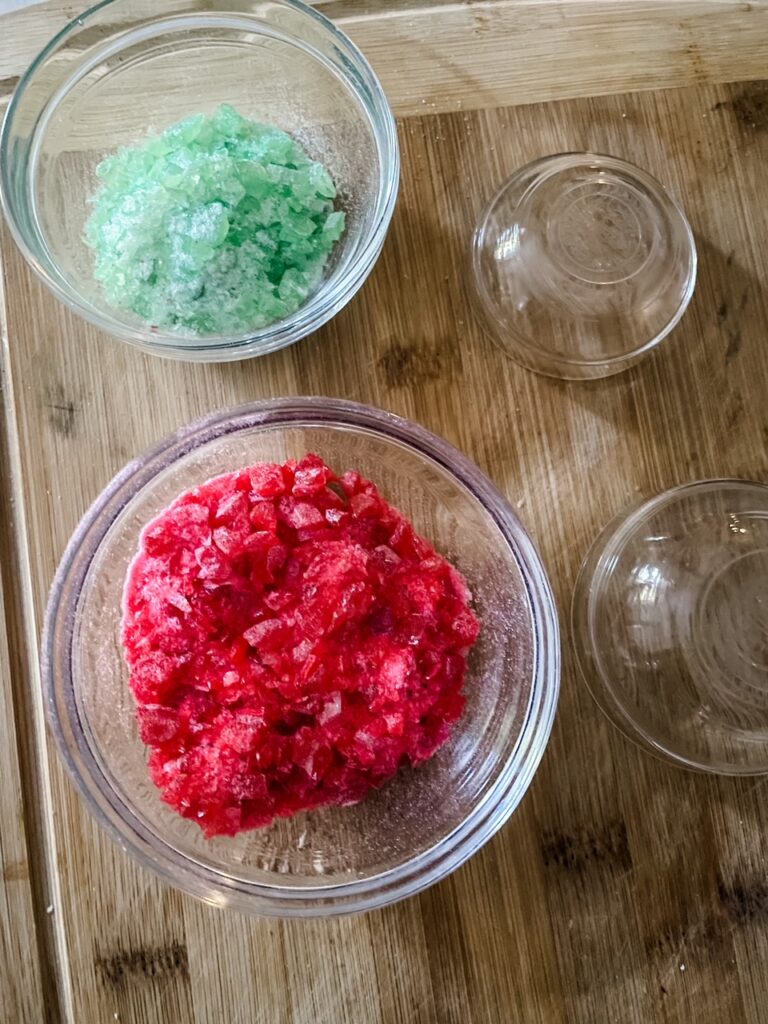 The crushed up red and green jolly ranchers in bowls, separated by color