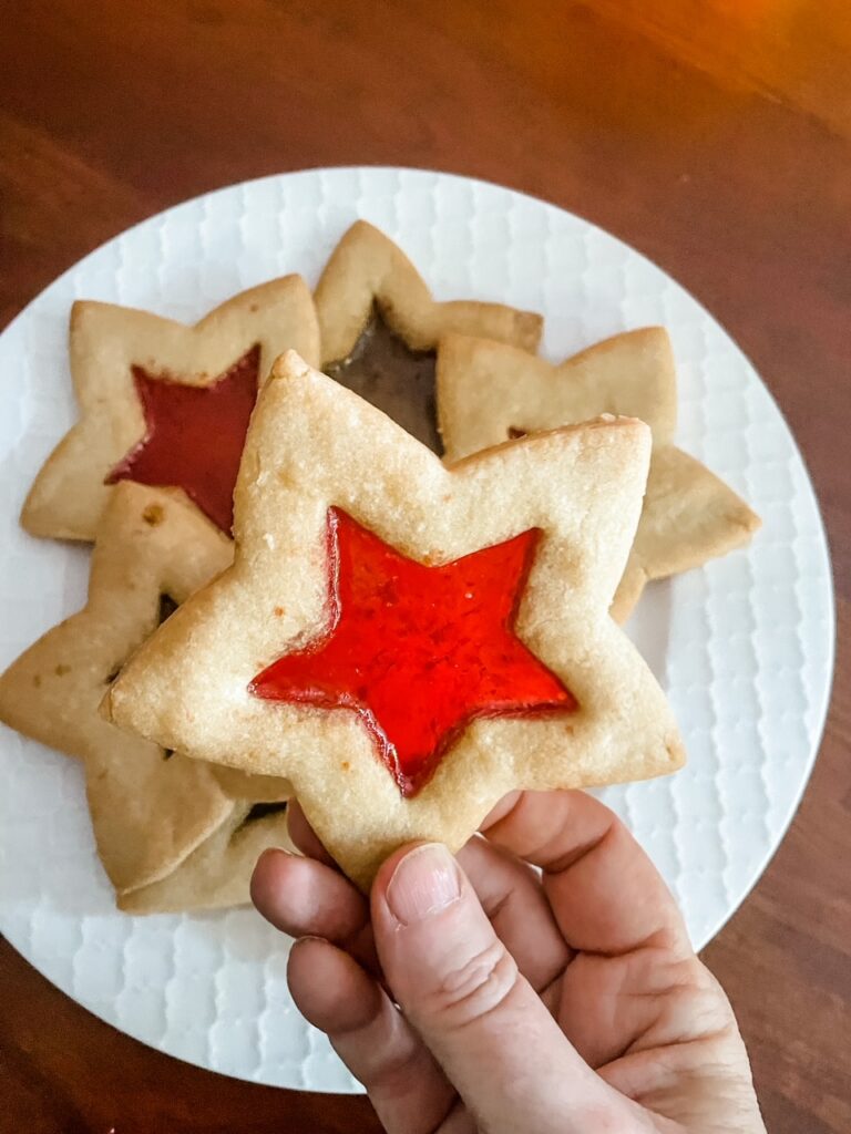 A hand holding up one of the Stained Glass Cutout Sugar Cookies