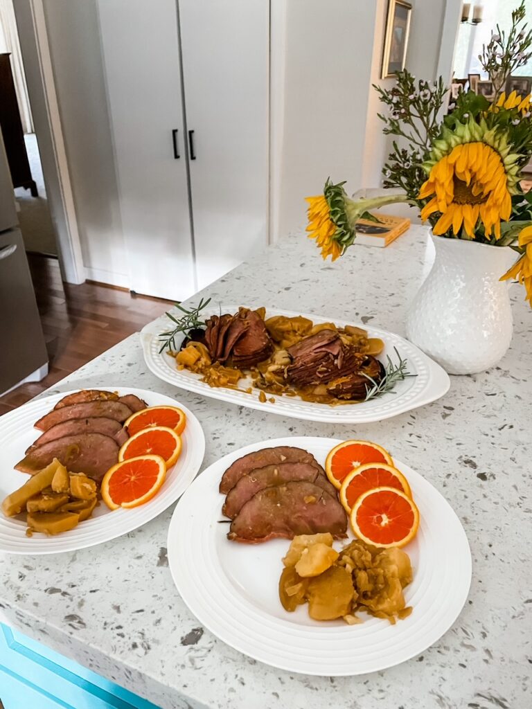 The platter of Citrus Slow Cooker Ham with two plates made up