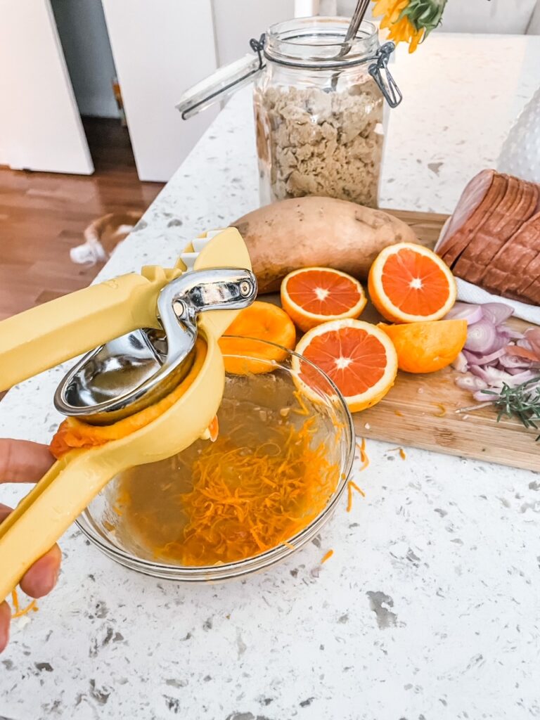A juicer squeezing fresh orange juice into a bowl of zest