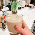 Marie holding up the finished Date and Banana Protein Smoothie with a straw