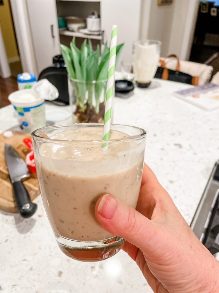 Marie holding up the finished Date and Banana Protein Smoothie with a straw