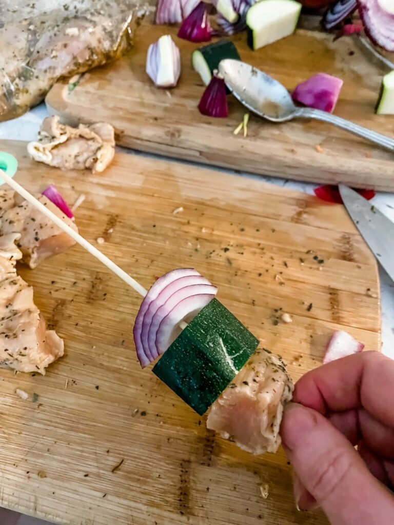 Marie threading the chunks of chicken and vegetables onto the skewer