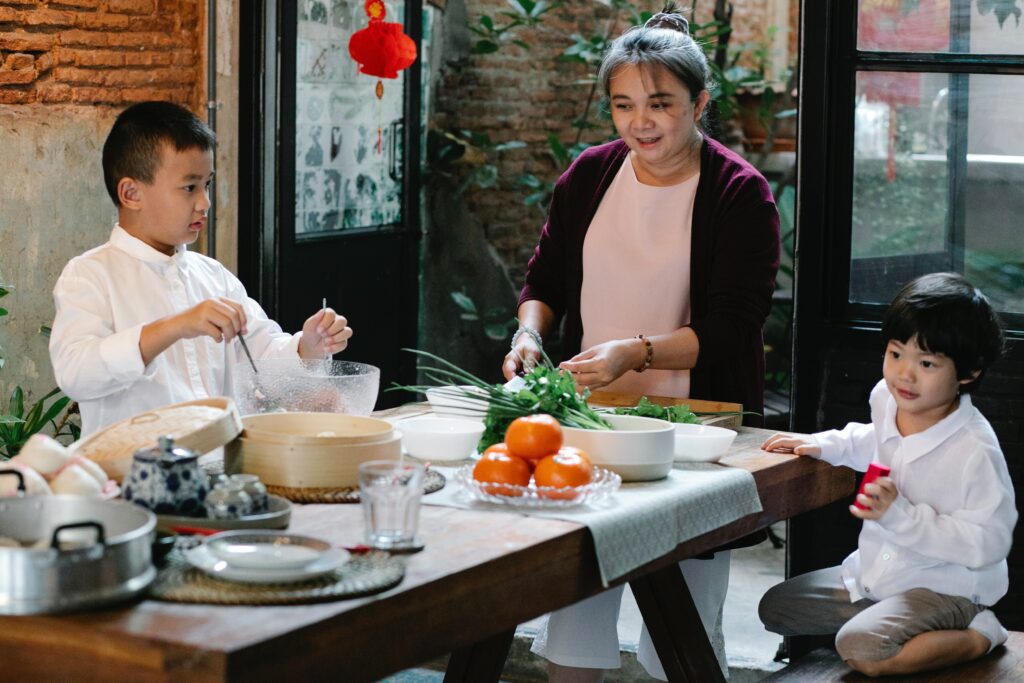 A grandmother and her two grandchildren cooking, using their connection as a method of handling aging