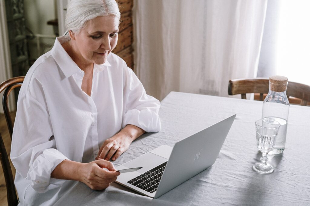 A woman sitting at a table using a laptop, using connection as a method of handling aging