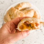 Marie holding up one of the finished Easy Cheesy Ham and Apple Hand Pies, cut in half