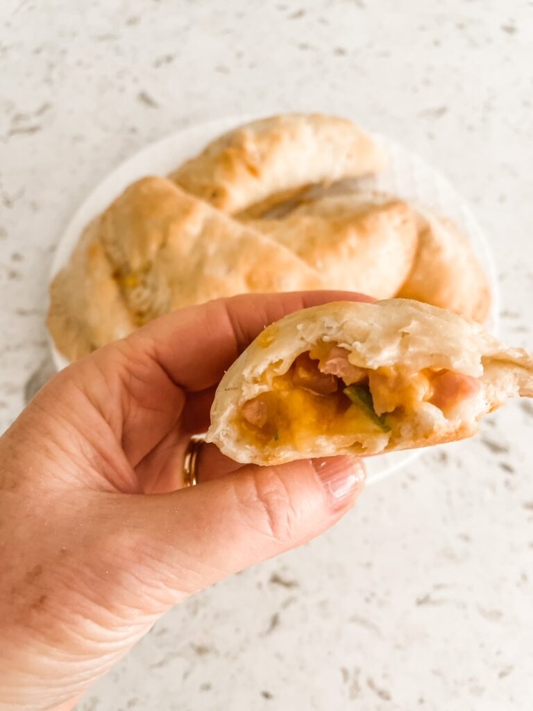 Marie holding up one of the finished Easy Cheesy Ham and Apple Hand Pies, cut in half