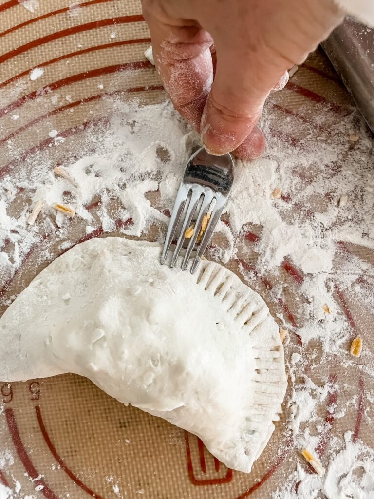 A fork sealing the crust of the pie 