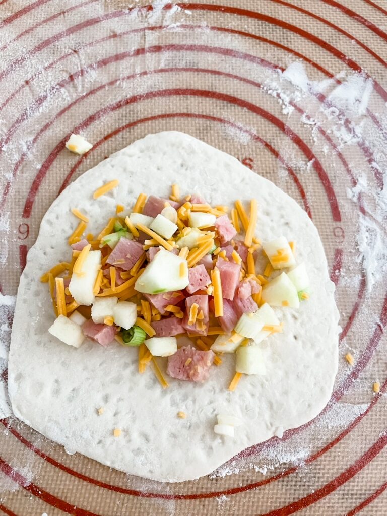 The stretched out pizza dough with the mixture in the middle