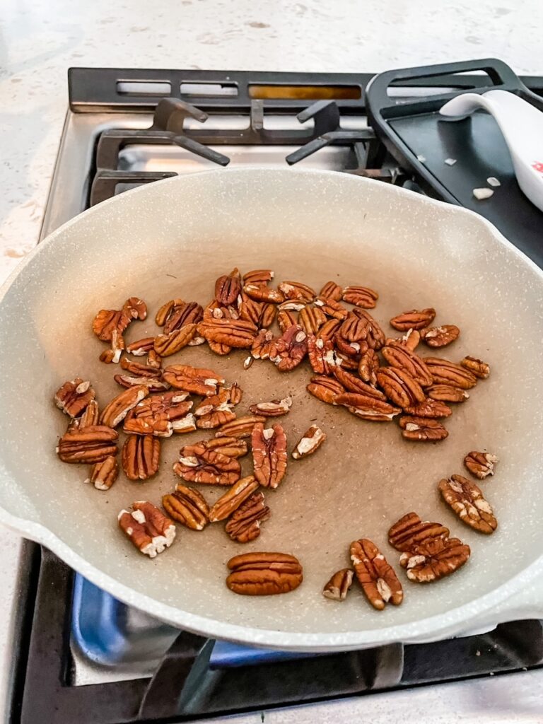 The pecans being lightly toasted in a pan